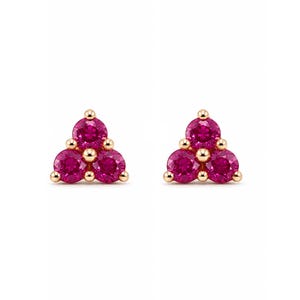 May include: A pair of stud earrings featuring three round, vibrant pink stones arranged in a triangular cluster. Each stone is set in a polished gold-tone metal setting with small, rounded prongs holding the gems securely in place.
