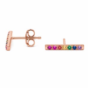 May include: Rose gold bar earrings with a row of colorful gemstones. The gemstones are arranged in a rainbow pattern, with pink, red, orange, yellow, green, blue, and purple stones. The earrings are a stud style.