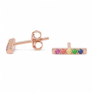 May include: Rose gold bar stud earrings with a row of colorful gemstones in a rainbow pattern. The earrings have a post and butterfly backing. The gemstones are pink, red, yellow, green, and blue.