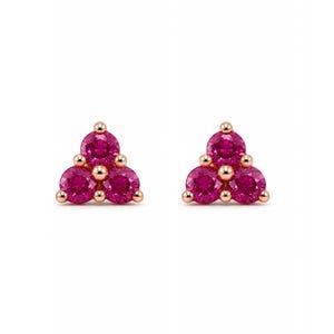 May include: A pair of stud earrings featuring three round-cut vibrant pink stones arranged in a triangular cluster. Each stone is set in a polished rose gold metal setting with small metallic prongs securing the gems in place.