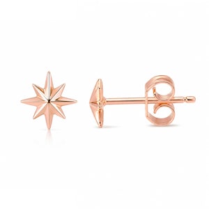 May include: A pair of rose gold stud earrings, each featuring an eight-pointed star design with faceted surfaces. One earring is shown from the front, while the other is displayed from the side, revealing the post and the secure butterfly back closure.