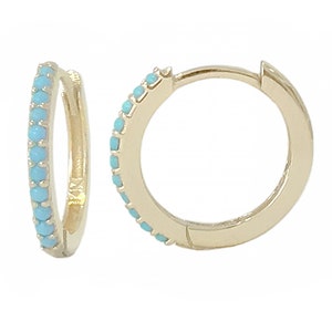 May include: Gold hoop earrings with a row of turquoise blue stones around the edge.
