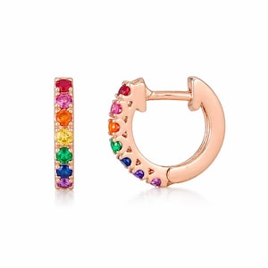 May include: Rose gold hoop earrings with a rainbow of colorful gemstones. The earrings feature a row of red, pink, orange, yellow, green, blue, and purple stones. The earrings are shown against a white background.