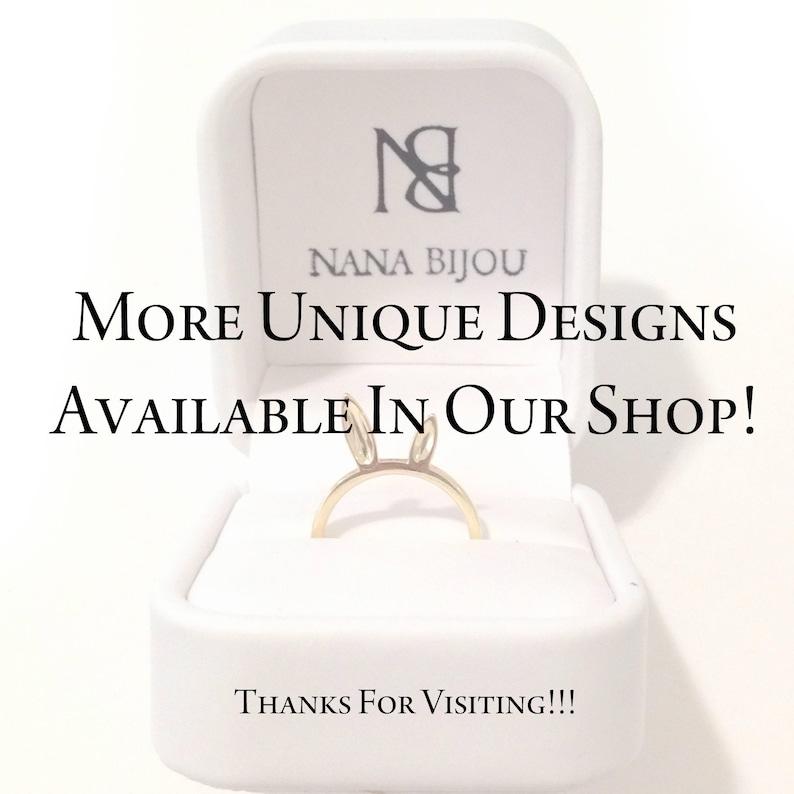 May include: A gold-toned ring featuring two small upright ears, presented in a white jewellery box. The box lid displays the text NANA BIJOU, while the centre text reads MORE UNIQUE DESIGNS AVAILABLE IN OUR SHOP! and the bottom reads THANKS FOR VISITING!!!