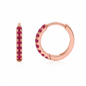Puede incluir: Un par de pendientes de aro en oro rosa con una hilera de pequeñas piedras preciosas redondas de color rosa vibrante engastadas a lo largo de la curva frontal de cada aro. Los pendientes tienen un mecanismo de cierre de bisagra y acabado pulido.