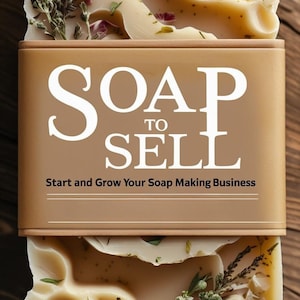 Puede incluir: Barra de jabón artesanal con detalles florales y herbales, incluyendo una flor morada. El jabón está envuelto con una banda marrón que dice "SOAP TO SELL" y "Start and Grow Your Soap Making Business". El jabón está sobre una superficie de madera.