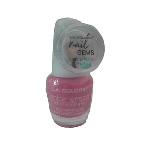 May include: A bottle of L.A. Colors Color Craze nail polish in a light pink shade with a hardener formula, featuring a clear plastic blister pack attached to the cap containing a small circular container of nail gems labeled L.A. Colors nail GEMS.