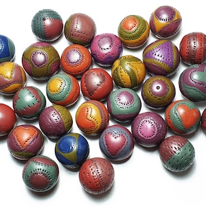 May include: A collection of 30 colourful, round, ceramic ornaments with various geometric and heart designs. Each ornament is painted with a combination of red, orange, yellow, green, blue, purple, and brown.