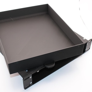 May include: Two black metal trays, one stacked on top of the other. The top tray is open, revealing a dark interior. The trays appear to be part of a larger system or structure, possibly for storage or organization.