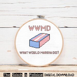 May include: A cross-stitch embroidery hoop featuring a pixelated design in the colors of the transgender flag. The text "WWMD" and "WHAT WOULD MARSHA DO?" are stitched above and below the flag design. The text "The Stitch is Political DIGITAL DOWNLOAD" is at the bottom.