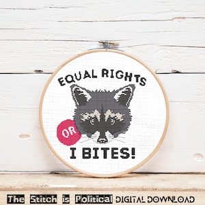 May include: Cross stitch pattern featuring a raccoon with the text "Equal Rights or I Bites!" in black and white on a white background.