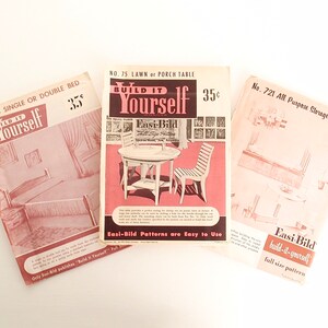 May include: Three vintage "Build It Yourself" pattern booklets with illustrations of a bed, table and chairs, and a storage unit. The booklets are printed on pink paper with black and white illustrations. The text on the covers reads "Build It Yourself" and includes the pattern number and price.