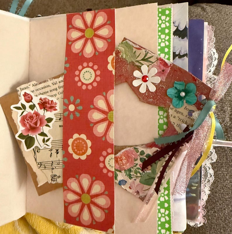 May include: A pink and white floral patterned scrapbook page with a variety of embellishments, including ribbons, flowers, and paper scraps. The page is decorated with a heart-shaped cutout and a quote from a song.