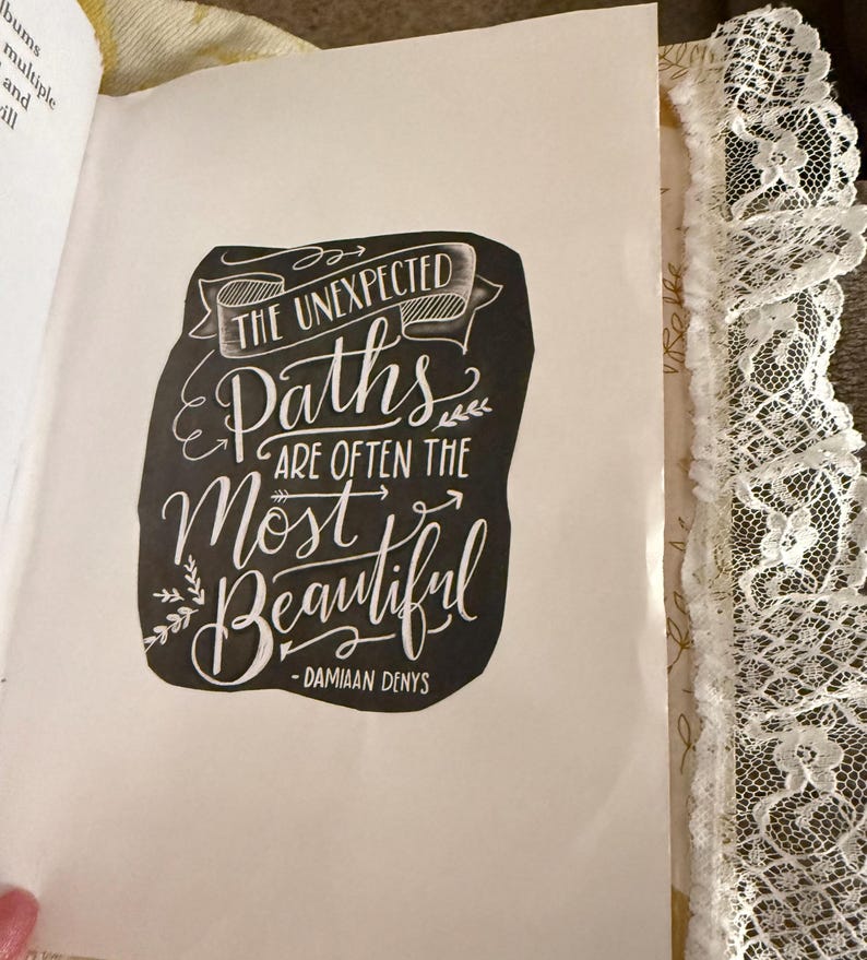 May include: Black and white typography quote on a white background. The quote reads "The unexpected paths are often the most beautiful - Damiaan Denys".