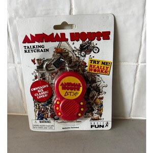 May include: Red and yellow Animal House talking keychain on a white and gray backing. The keychain has the words "Animal House" and "ATX" on it. The packaging reads "Talking Keychain" and "Contains Six Classic Lines!"