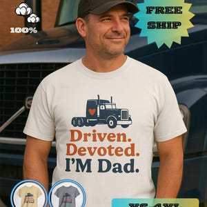 May include: A cream-coloured t-shirt featuring a navy blue truck graphic and the text "Driven. Devoted. I'M Dad." The truck has a red heart. The shirt is 100% cotton and available in sizes XS-4XL.