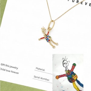 Op de afbeelding: Een goudkleurige hangerketting met een kleurrijk, kinderlijk figuurontwerp. De figuur heeft uitgestrekte armen en een patroonlichaam. De woorden "CHILD LOVE FOREVER" staan op de achtergrond.