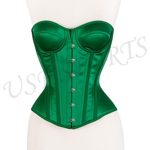 May include: A vivid green satin corset with a structured, strapless design. The corset features vertical boning, a row of silver clasps down the front, and a curved neckline. The garment is displayed on a white mannequin.