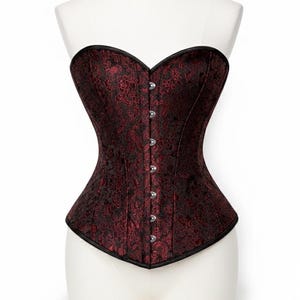 Un corsé negro con un estampado floral rojo, exhibido sobre un maniquí.