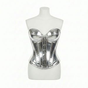 May include: A silver corset with a shiny, metallic finish. The corset has a sweetheart neckline and a row of small buttons down the front. It is displayed on a white mannequin.