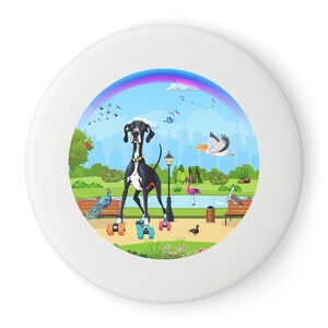 Pode incluir: Um frisbee branco com uma ilustração colorida de um cão preto e branco usando patins em um ambiente de parque. O cão é cercado por pássaros, um pavão, um flamingo e um poste de luz. O fundo apresenta um arco-íris e uma cidade.