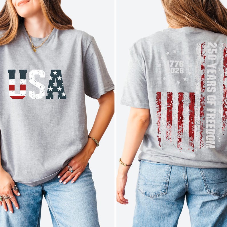 May include: A heather gray t-shirt featuring the text USA on the front in a distressed American flag pattern. The back displays a vertical distressed American flag graphic with the text 250 YEARS OF FREEDOM and the years 1776 and 2026.