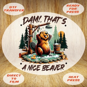 May include: A round DTF transfer design featuring a cartoon beaver taking a shower. The beaver is brown with a happy expression, standing in a pool of water. The text "DAM! THAT'S A NICE BEAVER" is displayed.