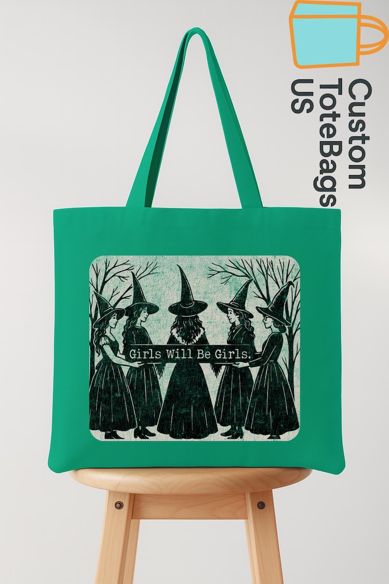 May include: A green tote bag with a rectangular graphic featuring five women in witch hats and dresses, holding hands. The text "Girls Will Be Girls" is below the image. The bag has a matching green handle.