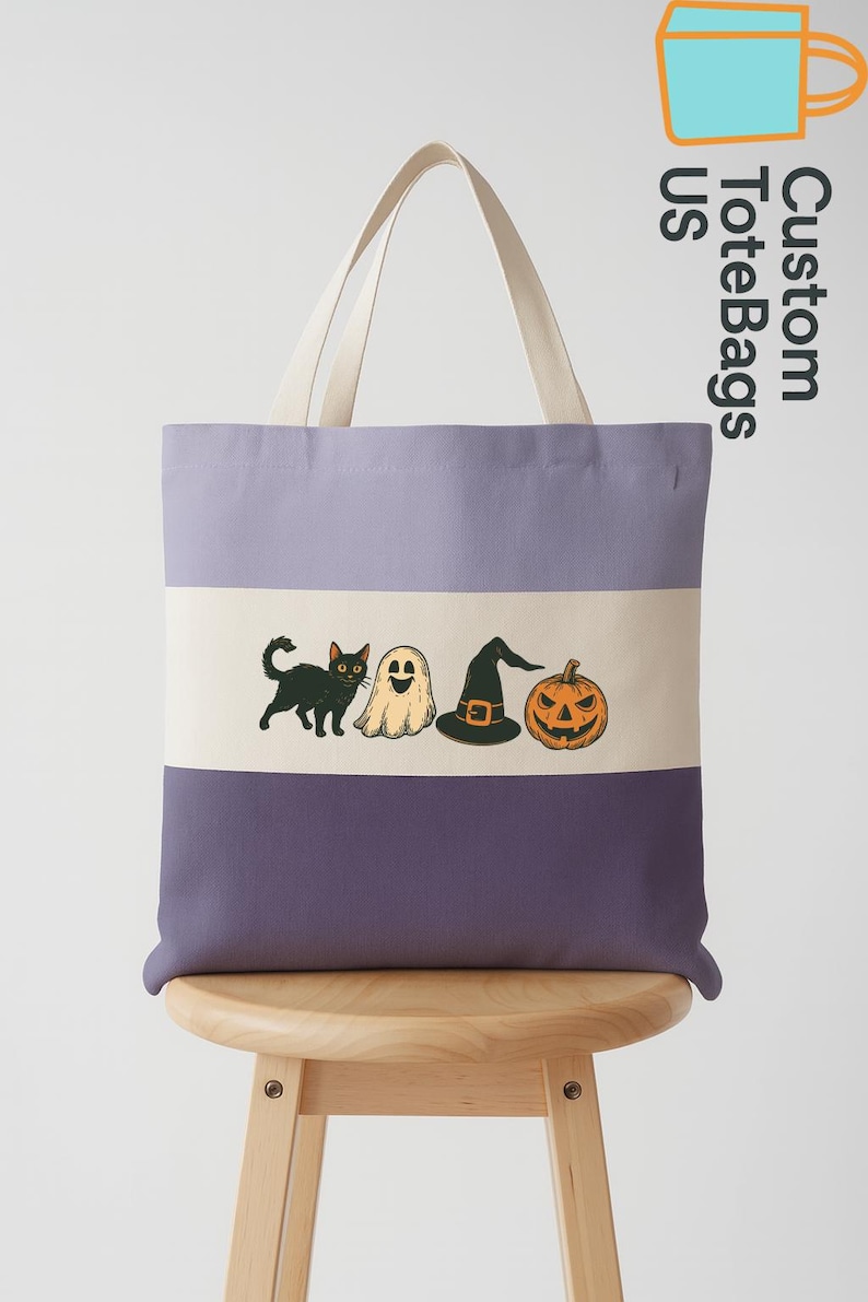 May include: A purple and cream tote bag with a Halloween-themed design. The bag features a black cat, ghost, witch hat, and jack-o'-lantern. The text "Custom Tote Bags US" is printed on the side. The bag has cream-colored handles.