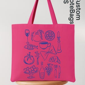 May include: A bright pink tote bag with blue line art illustrations of food and drink items. The bag features a wine glass, fish, coffee cup, pasta, tomato, grapes, and more. The text "Custom Tote Bags US" is printed on the side.
