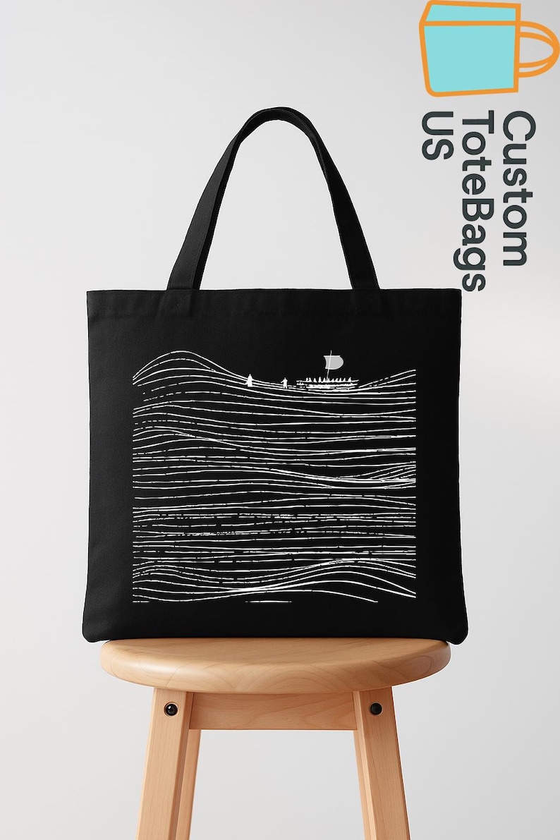 Puede incluir: Bolso tote negro con un dibujo lineal blanco de un barco navegando sobre l&iacute;neas onduladas. El bolso tiene dos asas negras y una forma rectangular. Las palabras "Custom Tote Bags US" est&aacute;n impresas en la esquina superior derecha.