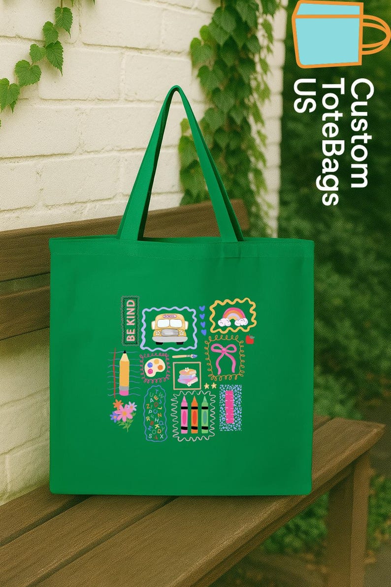 May include: A green tote bag featuring school-themed illustrations such as a bus, rainbow, and crayons. The bag has the text "BE KIND" and "Custom ToteBags US".