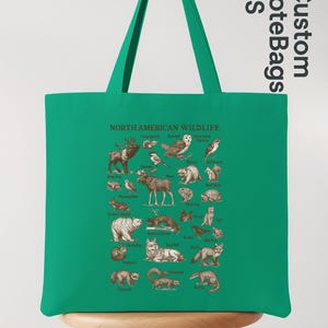 May include: A green tote bag displaying an illustrated guide to North American wildlife. The design includes animals like deer, birds, and bears, each labelled. The bag has long green handles and the text "NORTH AMERICAN WILDLIFE". The bag is made of a durable material.