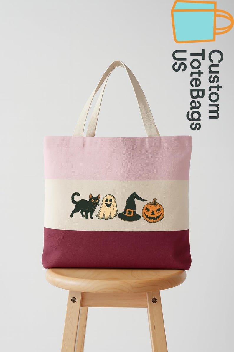 May include: A striped tote bag with a pink, beige, and burgundy color scheme. The bag features a Halloween-themed graphic of a black cat, ghost, witch hat, and jack-o'-lantern. The text "Custom Tote Bags US" is printed on the side.