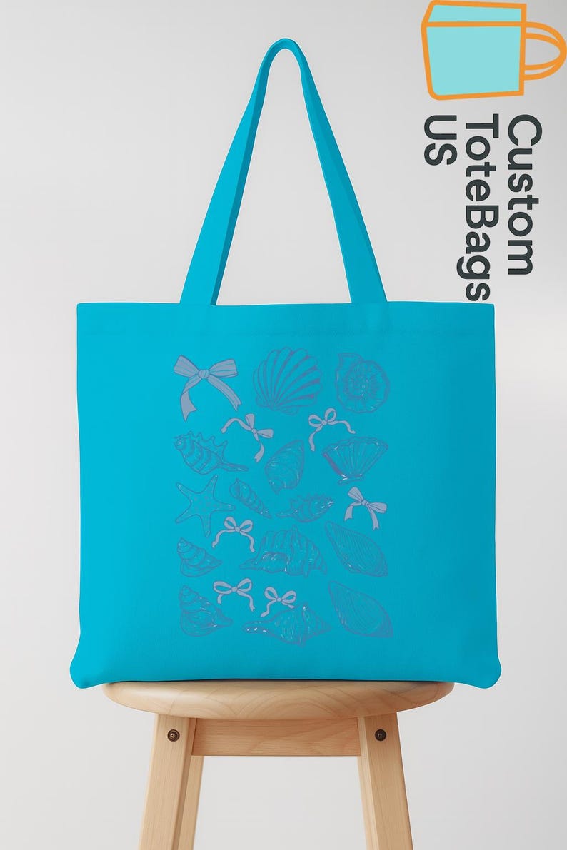 K&ouml;nnte beinhalten: Eine t&uuml;rkisblaue Tragetasche mit einem Muschel- und Schleifenmuster. Die Tasche hat eine rechteckige Form mit einem passenden t&uuml;rkisblauen Griff. Die Worte "Custom Tote Bags US" sind auf der Seite aufgedruckt. Die Tasche steht auf einem Holzschemel.