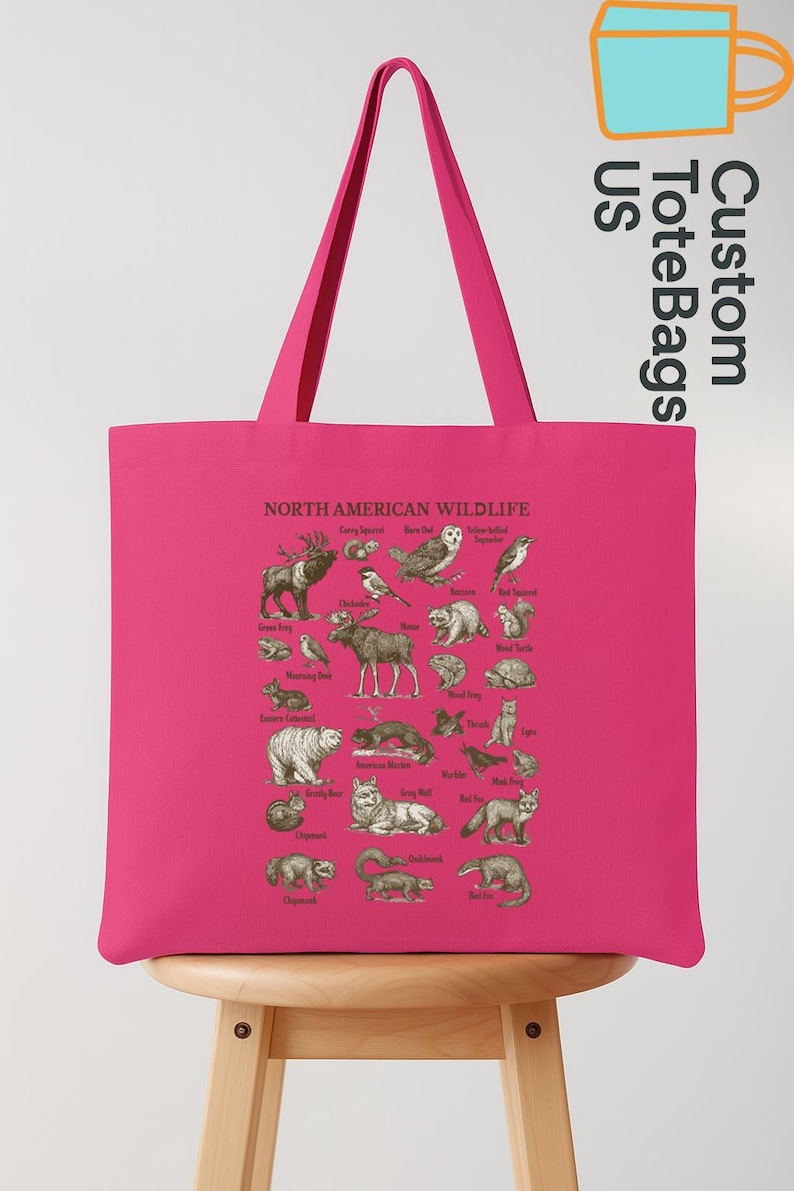May include: A vibrant pink tote bag displaying an illustration of North American wildlife. The bag features various animals with their names, ideal for nature lovers. The bag has long handles.