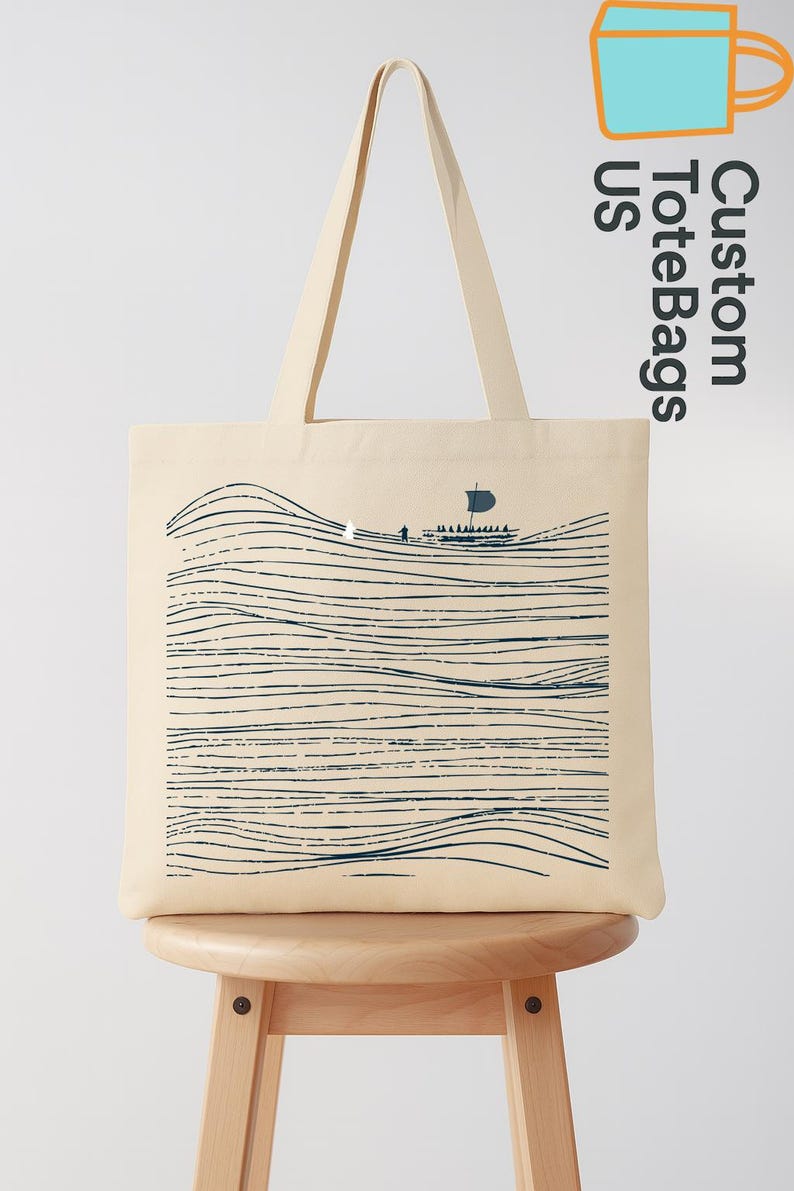 Puede incluir: Bolso tote de color crema con una ilustraci&oacute;n azul marino de un barco navegando sobre l&iacute;neas onduladas. El bolso tiene asas largas y el texto "Custom Tote Bags US" en orientaci&oacute;n vertical.