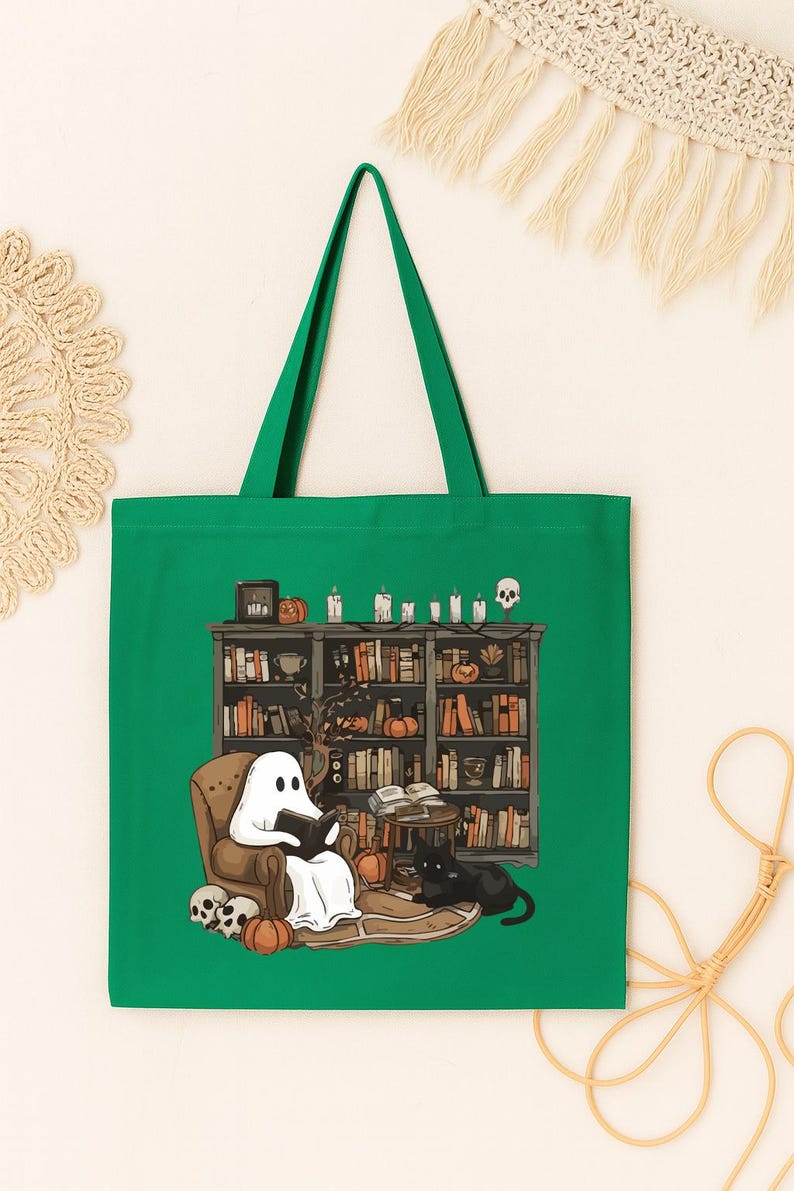 Puede incluir: Bolso tote verde con una ilustraci&oacute;n caprichosa de un fantasma leyendo en una biblioteca. La escena incluye un gato negro, calabazas, velas y una estanter&iacute;a llena de libros. Un dise&ntilde;o divertido y espeluznante para los amantes de los libros.