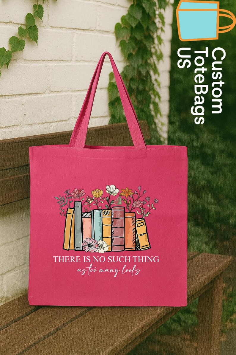 May include: A pink tote bag featuring a colorful illustration of books with flowers growing out of them. The text "THERE IS NO SUCH THING as too many books" is below the illustration. The bag has pink handles.