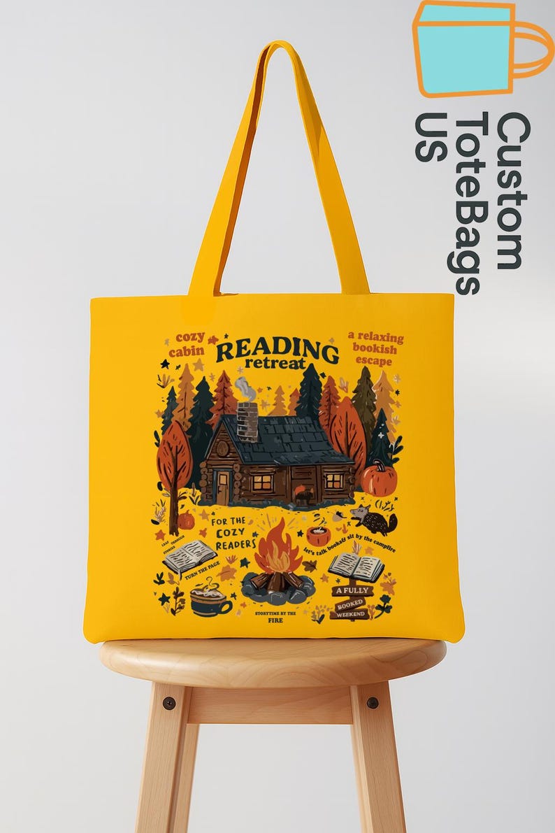 May include: Mustard yellow tote bag featuring a cabin scene with the words "Reading Retreat." The design includes a cabin, trees, a campfire, and the text "For the Cozy Readers." The bag has yellow handles and the text "Custom Tote Bags US."