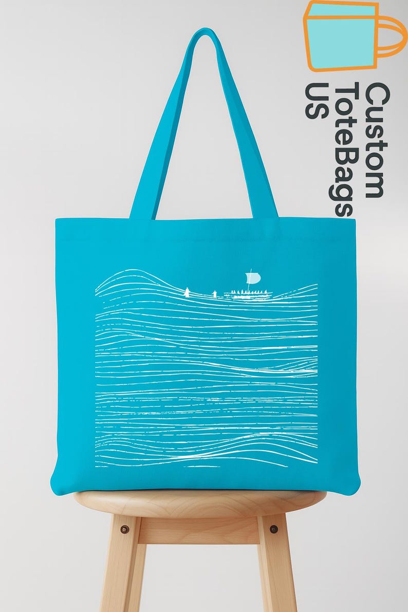 Puede incluir: Bolso tote turquesa con un dise&ntilde;o de olas y barco en blanco. El bolso tiene forma rectangular con asas a juego. El texto "Custom Tote Bags US" est&aacute; impreso en el lateral. El bolso est&aacute; sobre un taburete de madera.