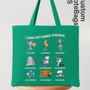 May include: A green tote bag with the text "I CAN DO HARD THINGS" and illustrations of cartoon characters. The bag also has the text "Custom ToteBags US".