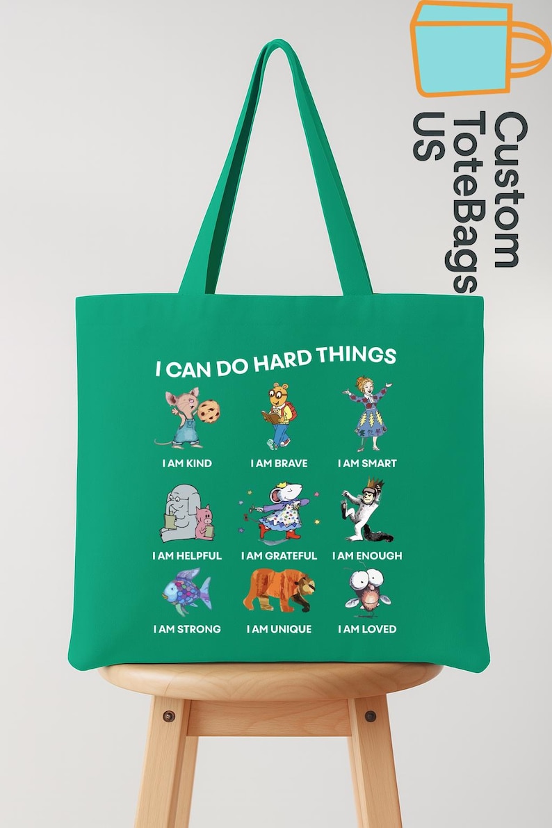 May include: A green tote bag with the text "I CAN DO HARD THINGS" and illustrations of cartoon characters. The bag also has the text "Custom ToteBags US".