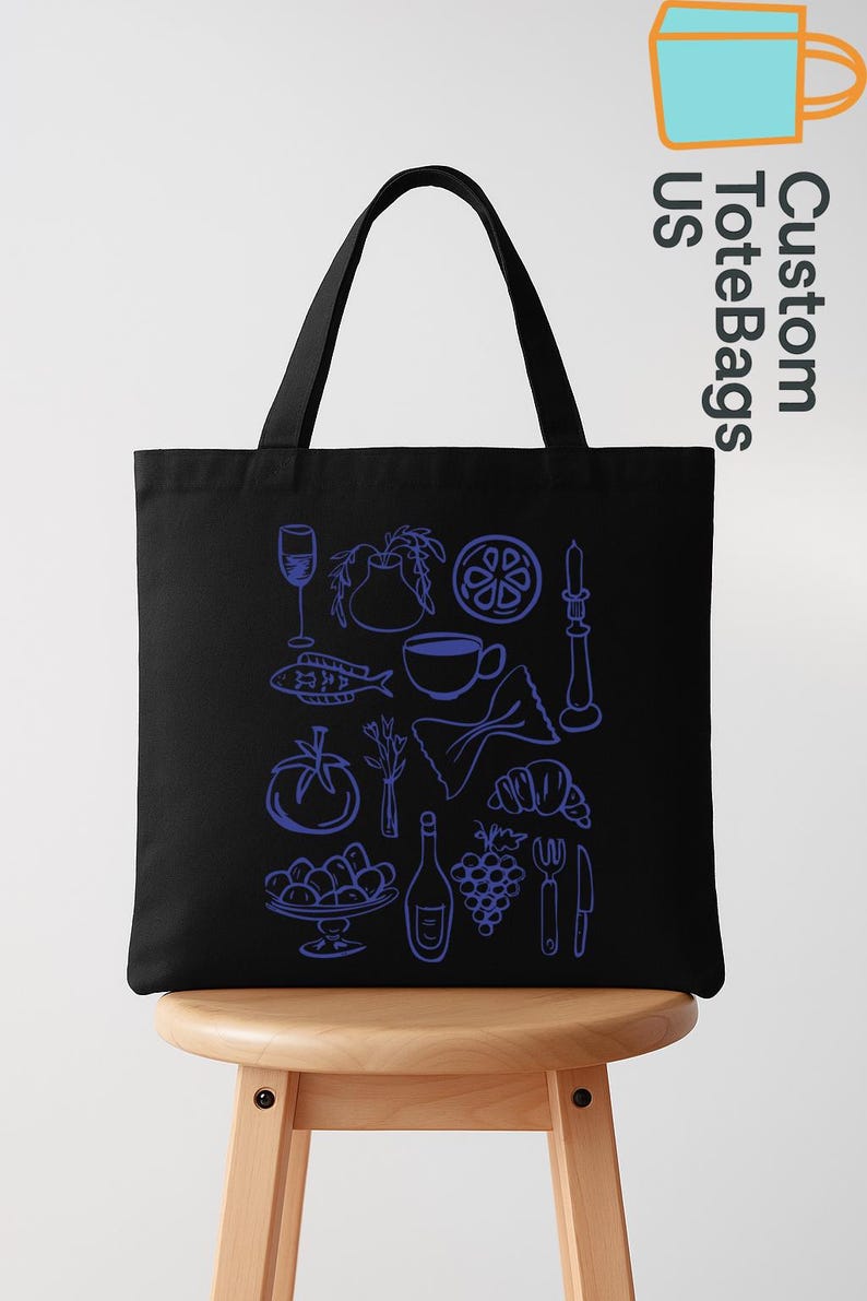 May include: Black tote bag with a blue line drawing of various food items, including a wine glass, fish, tomato, pasta, and grapes. The bag has a handle and the text "Custom Tote Bags US" in the upper right corner.