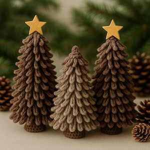 May include: Three handmade crochet Christmas trees in varying shades of brown. Each tree is topped with a gold star. The trees are arranged in a group, with pine cones in the background. A festive, handcrafted holiday decoration.