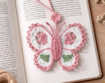 May include: A handmade crochet butterfly bookmark in pink, white, and green. The butterfly has detailed wings and a delicate design, perfect for marking pages in a book. The bookmark is a charming accessory.