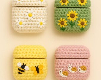 Könnte beinhalten: Vier gehäkelte AirPod-Hüllen. Die Hüllen sind cremefarben mit Gänseblümchen, grün mit Sonnenblumen, gelb mit Bienen und Schmetterlingen und rosa mit Schnecken. Jede Hülle hat einen passenden Deckel.
