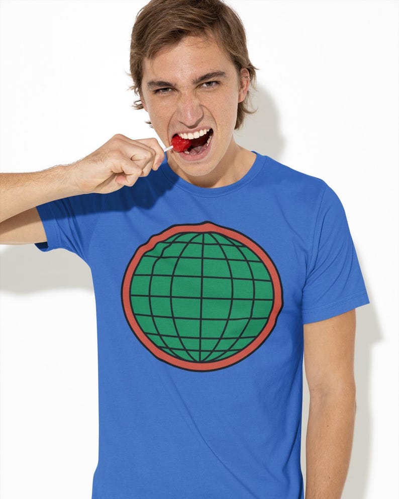 May include: A blue short-sleeved t-shirt featuring a central graphic of a green globe with black grid lines, enclosed within a thick red circular border. The design is printed on the chest of the garment, which has a standard crew neckline.