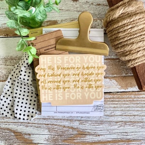 Puede incluir: Una pegatina beige con texto dorado que dice "HE IS FOR YOU may His Presence go before you and behind you, and beside you all around you, and within you He is with you. He is with you HE IS FOR YOU NUMBERS 6.24-26".