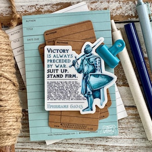 May include: A blue and white sticker with a knight in armor and the text "Victory is always preceded by war. Suit up. Stand firm."  The sticker also includes a Bible verse from Ephesians 6:10-13.
